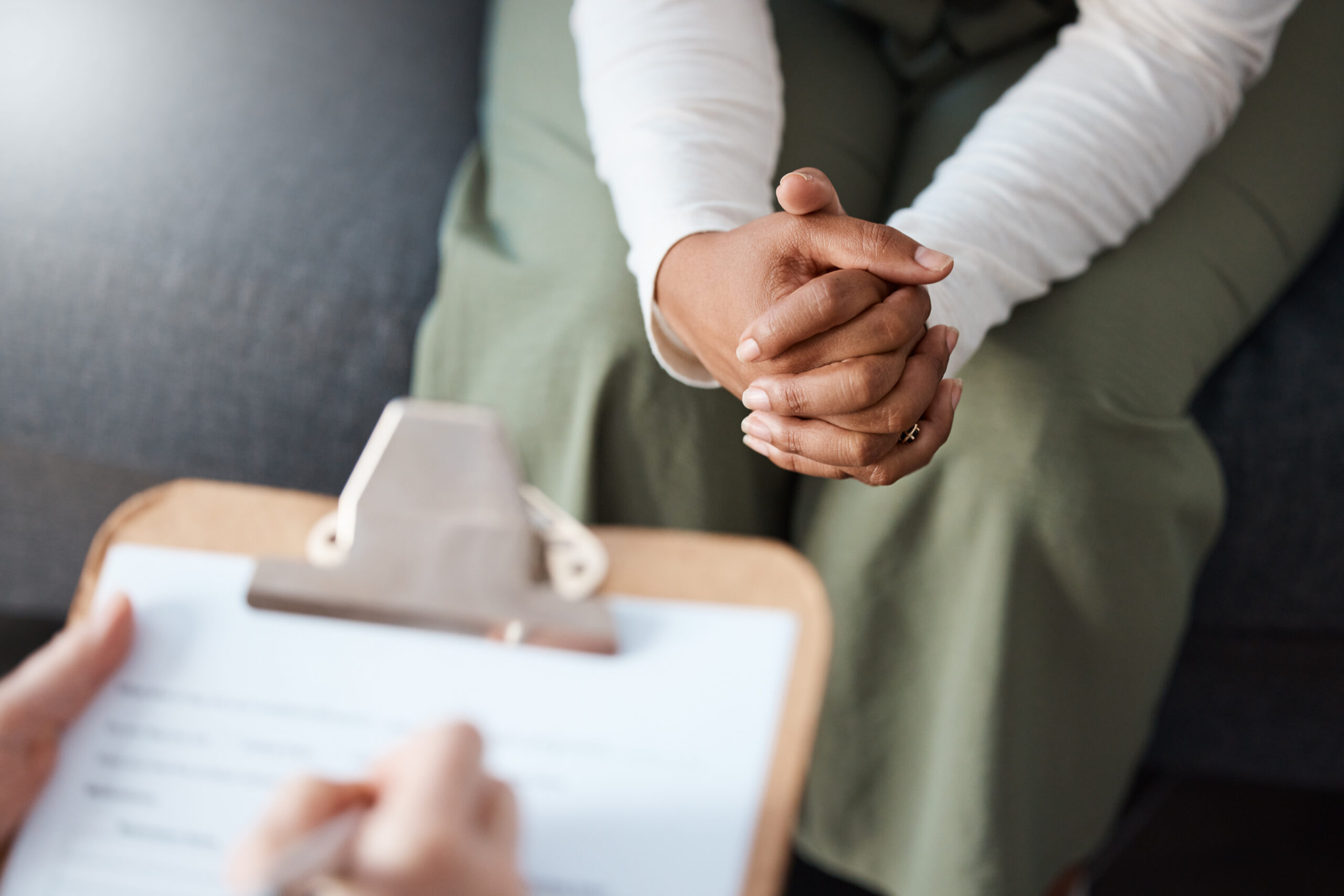 Woman, hands and therapist writing on clipboard in consultation for mental health, psychology or healthcare. Hand of female person or psychologist consulting patient with anxiety or stress in therapy Psychological Assessment